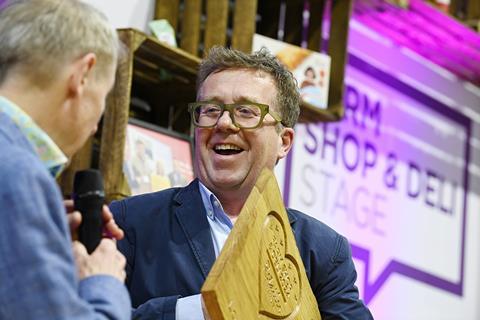 Lovingly Artisan co-founder Aidan Monks receives the trophy for Retailer of the Year at the Farm Shop & Deli Awards 2024  - William Reed