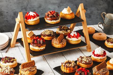 Doughnuts with whipped cream, chocolate and strawberries on top on a slate stand