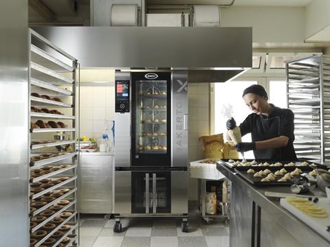 The Unox BakerTop-X oven with a female baker decorating croissants nearby in a professional kitchen