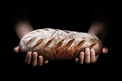 Hands holding a loaf of floured artisan bread