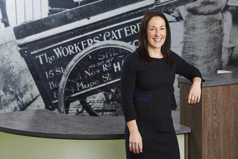 Helen Bowyer smiling in a black dress against a black & white photo