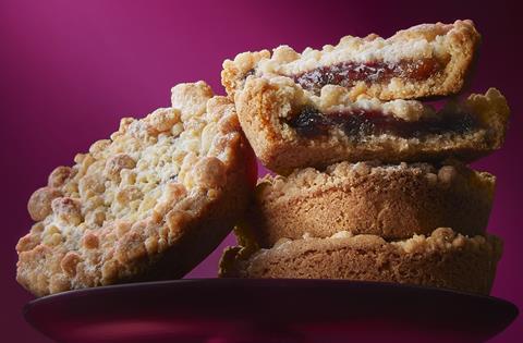 A stack of crumble-topped mince pies on a pink background