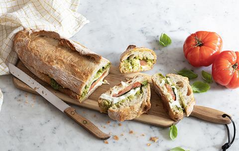 A giant sharing sandwich stuffed with pesto, tomato, and mozzarella