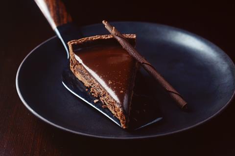A slice of chocolate ganache tart on a black plate