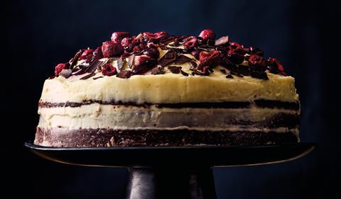 Black Forest Cake with cherries on top on a black cake stand