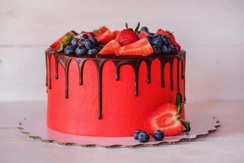 A red cake topped with berries and a chocolate drip
