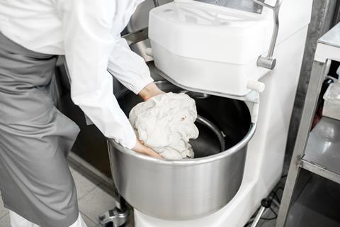 Baker taking dough out of an industrial mixer