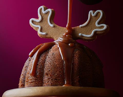 A Sticky Toffee Gingerbread Pudding with gingerbread reindeer antlers on top and a toffee sauce being drizzled over it