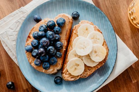 Two slices of toast with peanut, blueberries and banana on top