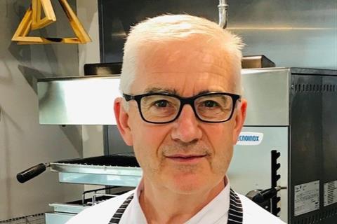Trevor Holmes - a white haired man with black rimmed glasses in a kitchen