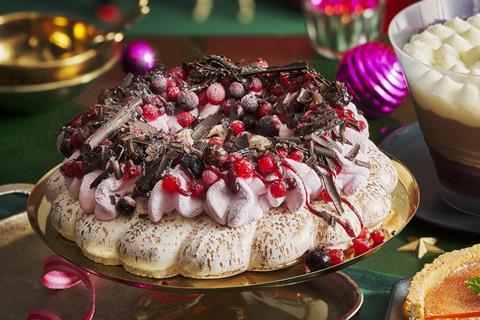 A meringue topped with cream, frozen berries and chocolate shavings