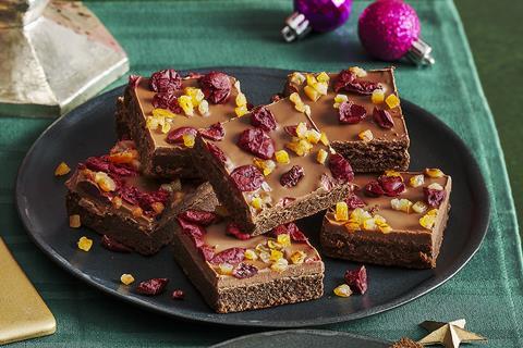 A plate of chocolate brownies topped with orange peel and dried cranberries