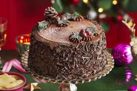 A festive chocolate cake with chocolate shavings on the side and edible holly and ivy leaves on top