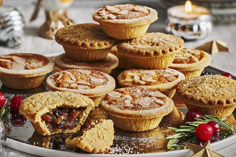 A pile of lovely golden mince pies with candles in the background