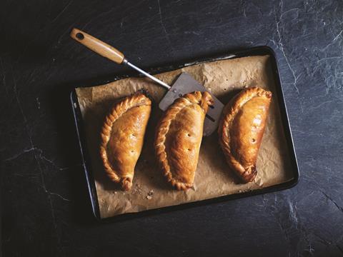 Three golden brown Cornish pasties on a metal baking tray