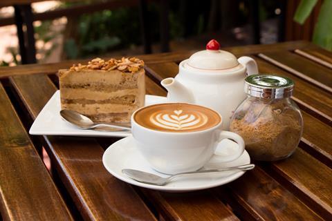 A cappuccino, slice of cake and a tea pot