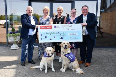 People holding a large cheque with two guide dogs in front
