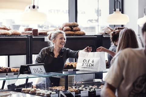 A woman handing a bag of baked goods to another woman