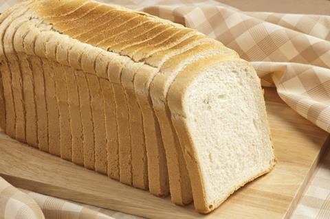 Sliced white bread on a wooden chopping board with chequered table cloth