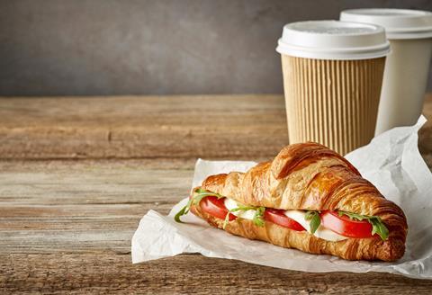 A filled savoury croissant and takeaway coffee cup