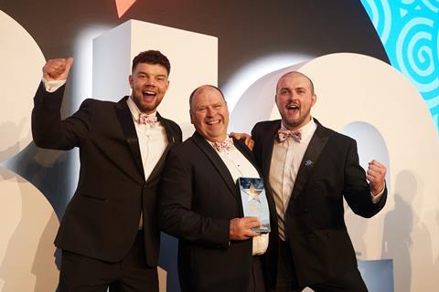 Three men in tuxedos celebrating winning an award