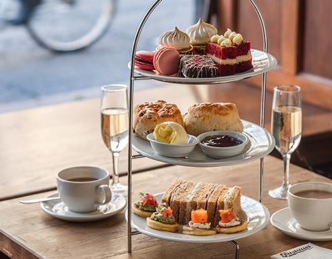 An afternoon tea stand loaded with macarons, scones, cakes and sandwiches