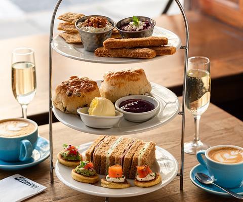 An afternoon tea stand loaded with savoury treats including scones, cheese straws, and sandwiches