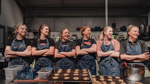 Six women bakers in matching denim aprons