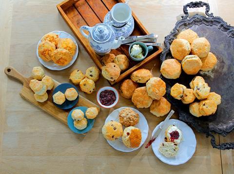 A birds eye view of lots of scones with jam and cream next to them