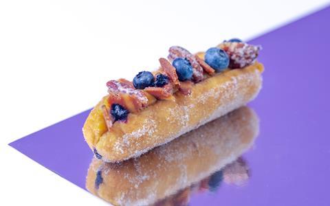 A finger-style doughnut topped with blueberries and fake bacon