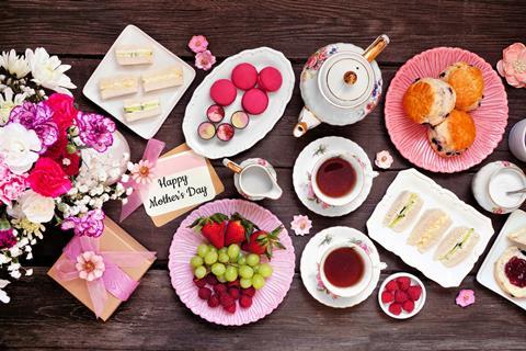 A Mother's Day themed afternoon tea with macarons, flowers, scones, and finger sandwiches