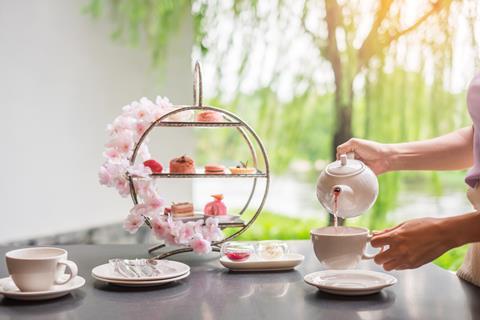 An afternoon tea stand with pink flowers around it