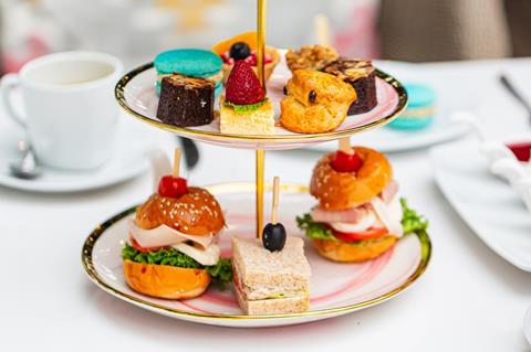 Brownies, blue macarons, strawberry topped cakes and brioche sandwiches on an afternoon tea stand