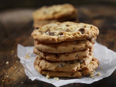 A stack of golden chocolate chip cookies on a wooden table