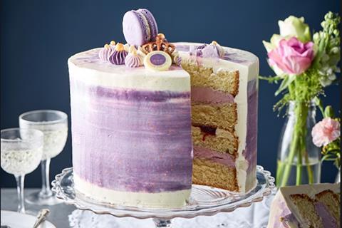 A four layer cake with purple buttercream and purple decorations