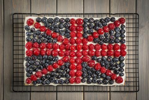 A sponge cake topped with white buttercream and raspberries and blueberries