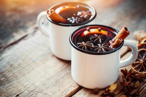 Mulled wine in mugs with cinnamon and orange