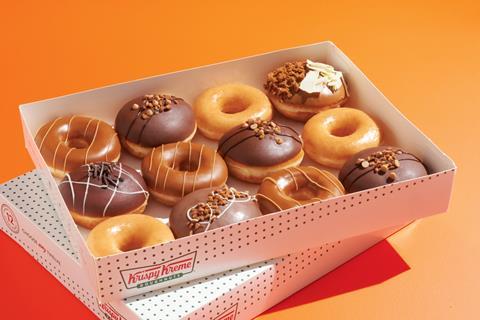 A dozen doughnuts in a box with Reese's peanut butter toppings