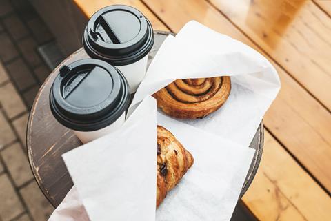 Pastries in paper bags next to two takeaway coffee cups