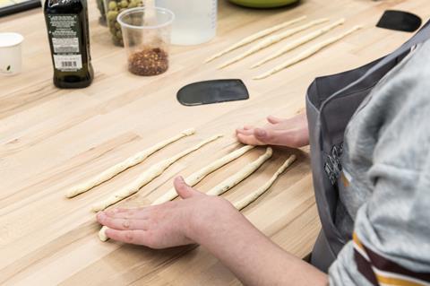 A young girl rolls out breadsticks at the Bread Ahead Baking School in Borough Market, London