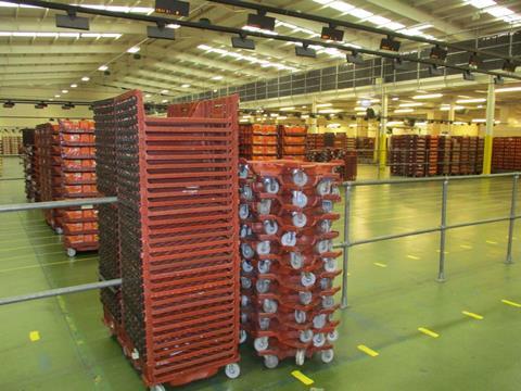 Brown plastic bread baskets and wheeled dollies stacked in a warehouse