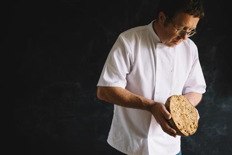 Aidan Monks from Lovingly Artisan lovingly holding a loaf of sourdough