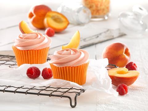 Cupcakes swirled with peach melba frosting and topped with fresh peaches