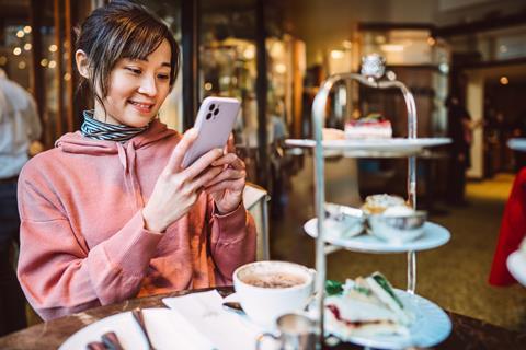 A young Asian woman taking photos of food and sharing them on social media