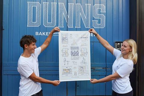Dunns tea towel being held up by two staff members