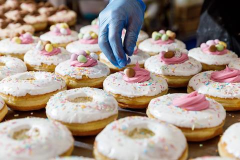 Doughnuts being topped with pink frosting and mini eggs at Project D