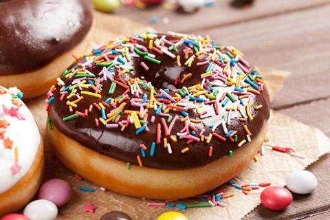 A chocolate topped doughnut with colourful sprinkles on top