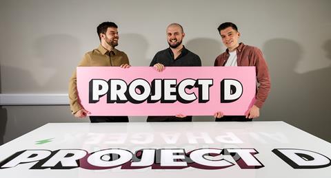 Project D founders (l-r) Matt Bond, Jacob Watts, Max Poynton holding a pink sign that says 'Project D'