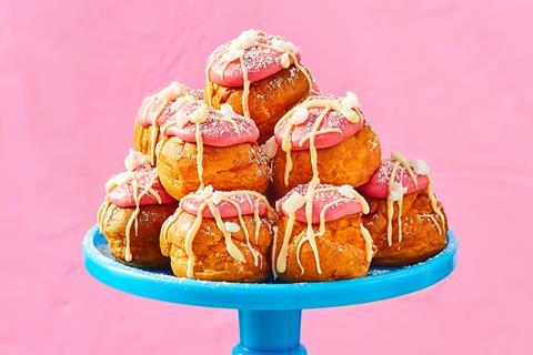 Profiteroles with pink fondant and white chocolate on a blue cake stand