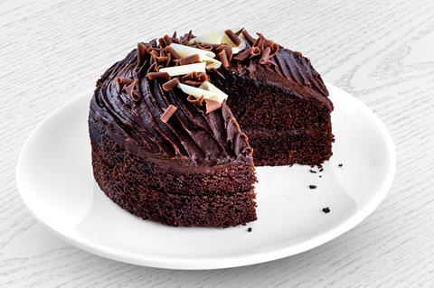 A chocolate sponge cake with chocolate frosting and chocolate curls on top